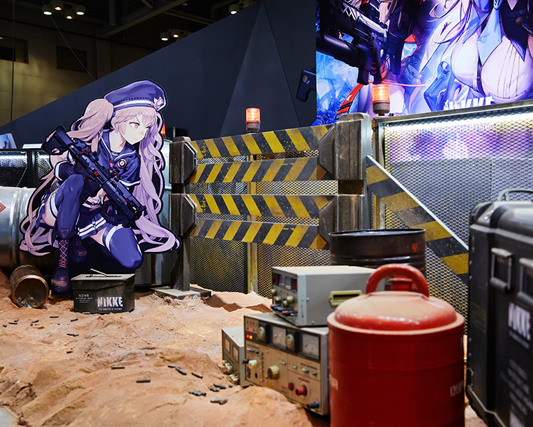 2021 SHIFT UP Nikke G-star booth design: photo zone with barriers, drums in the sand